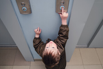 A small child presses the elevator call button. Baby reaches for the elevator button in a residential building. Kid aged about two years (one year ten months)