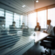 A group of employees are sitting in a meeting room through a blurred lens.