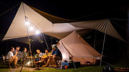 Wall Mural - Group of Happy Asian people friends enjoy and fun outdoor lifestyle hiking and camping together on holiday travel vacation. Man and woman couple having dinner together near the tent at summer night.