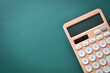 © sutichak - modern peach colour pastel calculator and white button on green background, business and finance accounting concept