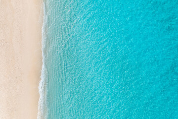 Summer seascape beautiful waves, blue sea water in sunny day. Top view from drone. Relax sea aerial view amazing tropical nature background. Tranquil bright sea waves splashing beach sand sunset light