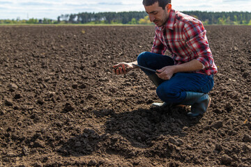 Canvas Print - Male farmer in the field checks the soil. Selective focus.