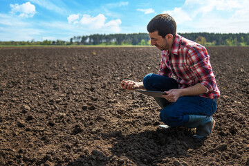 Canvas Print - Male farmer in the field checks the soil. Selective focus.