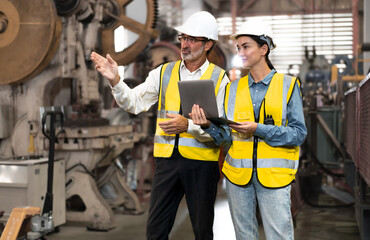 Wall Mural - Senior manager train female technician to work in metalwork production factory. Industrial engineer man and woman standing in manufacturing facility talking machinery technology in heavy industry.