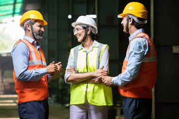 group of indian engineers wearing helmet and vest discussing and laughing, candid moment, industrial