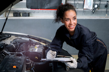 Wall Mural - Beautiful female auto mechanic working in garage, car service technician woman holding file paper and checking car engine, repairing customer car at automobile service, inspecting vehicle engine.