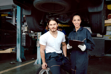 Wall Mural - Two mechanic workers working at garage, happy smiling technician man and woman checking and repairing customer car at automobile service center together, vehicle repair service shop concept.