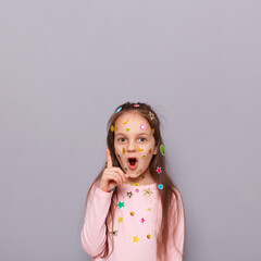 excited inspired little girl covered colorful kid's stickers standing isolated over gray background 