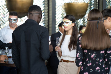 Wall Mural - Masquerade party. Beautiful women and men wearing fantasy mask. Company employee enjoy drinking in mask party  together indoors celebration