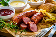 Fried sausages, onion and bread on wooden table
