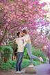 © Ivan - Happy stylish couple near blossoming sakura tree on city street. Spring family look