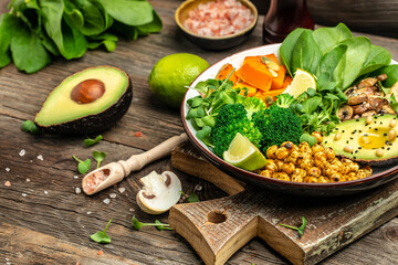 Wall Mural - healthy vegan lunch bowl with Avocado, mushrooms, broccoli, spinach, chickpeas, pumpkin on a wooden background. vegetables salad. Top view