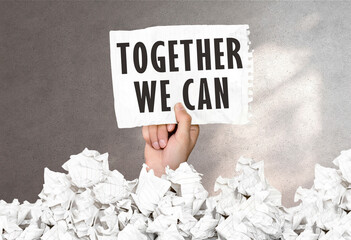 Poster - hand holds a piece of paper with text together we can on a gray wall background