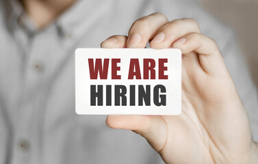 Poster - card with text we are hiring in a man's hand