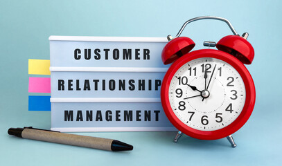 Poster - text customer relationship management written on the lightbox with alarm clock and colorfull sticker