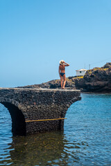 Wall Mural - A young woman on vacation in the seaside tourist village Tamaduste on the island of El Hierro, Canary Islands, Spain