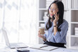© David - Cheerful business Asian woman freelancer making telephone call share good news about project working in office workplace, business finance concept.