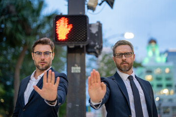 Businessmen doing stop sing with hand. Warning expression with negative and serious gesture. Stop hand gesture, businessman says hold on. Business man holding out hand, indicating stop on street.