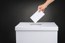 The Voter Holds His Vote Ballot Paper And Places It In The Ballot Box. Election Concept.