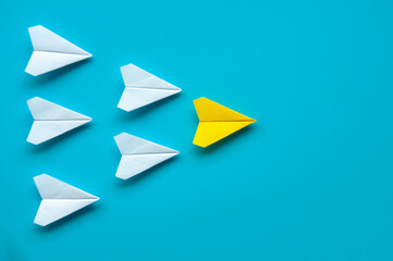 Wall Mural - Top view of paper airplane - Yellow paper airplane origami leading other white airplane on blue background.