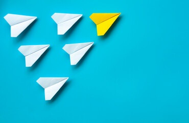Wall Mural - Top view of paper airplane - Yellow paper airplane origami leading other white airplane on blue background. Leadership concept.