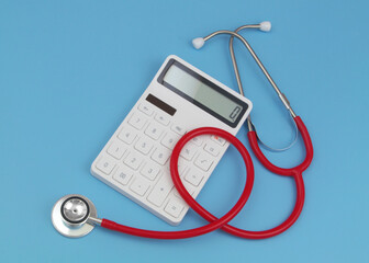 Red stethoscope with white calculator on blue background.