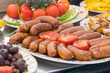 Street food in Ukraine - grilled  frankfurters lying on plate with tomatoes and mushrooms closeup