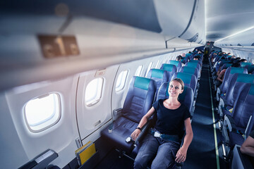 Wall Mural - Woman sitting in a flying aircraft. Passenger relaxing on the plane.