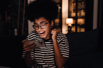 african woman screaming with joy while playing game on mobile phone