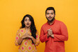 © Drobot Dean - Indian couple looking at camera with surprised faces expressions isolated over yellow background
