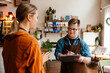 © Drobot Dean - Man with down syndrome writing down notes in clipboard while woman instructing him in his waiter duties