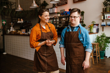 Wall Mural - Female waitress training man with down syndrome for work in cafe