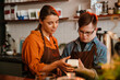 © Drobot Dean - Woman teaching man employee with down syndrome how to use payment terminal in coffee shop