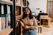 © Drobot Dean - Indian woman student smiling at camera while standing in library