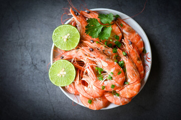 Wall Mural - Fresh shrimps prawns seafood lemon lime with herbs and spice, shrimp on white bolw and wooden background dining table food