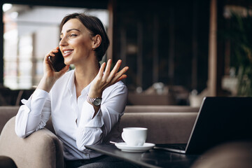 Canvas Print - Business woman in a cafe working on laptop and using phone