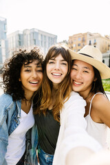 Young group of three diverse women taking selfie portrait with phone outdoors. Joyful millennial female friends enjoying day off at weekend in city street. Friendship concept Generative AI