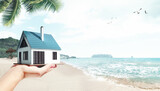 Fototapeta Kawa jest smaczna - Moving to island. Female hand holding 3D model of small comfortable house against beach, palms and ocean background. Concept of real estate, buying house, mortgage, ownership, business