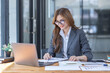 © David - Asian Business woman using calculator and laptop at workplace doing math finance on an office desk, tax, report, accounting, statistics, and analytical research concept