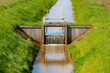 Irrigation concept, A small canal or ditch with little dam or water barrier for agriculture, Farmland in countryside of Holland with green grass meadow, Dutch water management system, Netherlands.