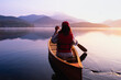 © Tetra Images - United States, New York, Rear view of woman paddling canoe on Lake Placid at sunrise, Adirondacks State Park
