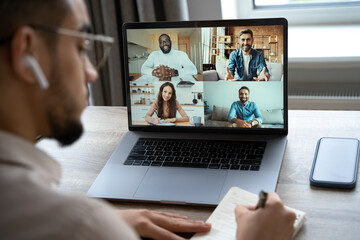 Back rear view of employee involved in video conference brainstorming meeting with diverse colleagues. Guy working from home using computer application for remote communication