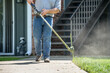 lawn care worker trimming grass along side walk with weed eater