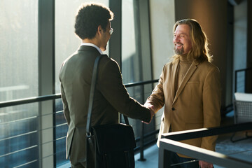 Aufkleber - Happy mature male lawyer shaking hand of young male colleague in elegant suit after negotiation while both looking at one another
