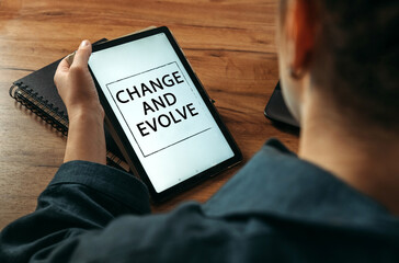 A woman holds a tablet in her hands on the screen of which it is written - Change and evolve