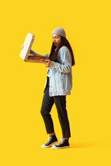 Canvas Print - Young woman with box of tasty pizza on yellow background