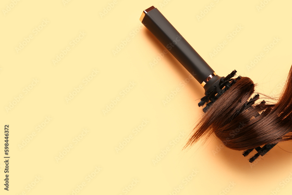 Brown hair with round brush on yellow background