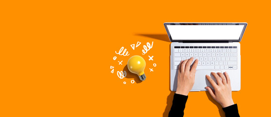 Wall Mural - Person using a laptop computer and a light bulb