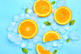 Fototapeta Kuchnia - Sliced fresh orange with mint and ice on blue background