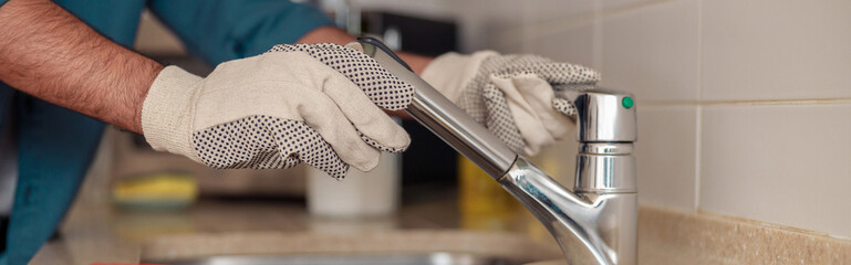 Male plumber repair sink faucet at customer kitchen. Maintenance and household assistance concept